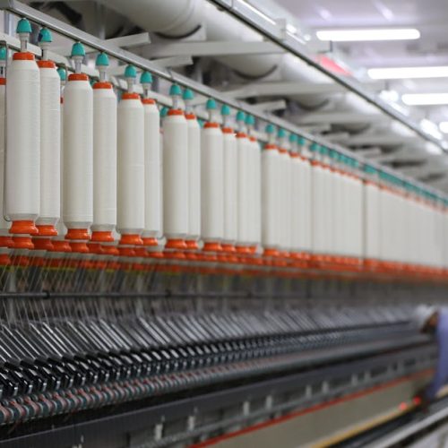 A textile factory in India showcasing modern spinning machinery with a worker.
